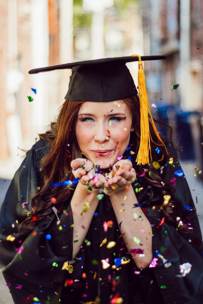 a person wearing a graduation cap and gown and holding a diploma