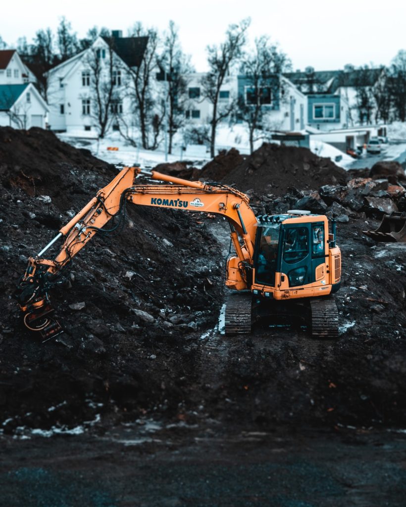 a yellow truck with a pile of dirt in the middle of a pile of mud