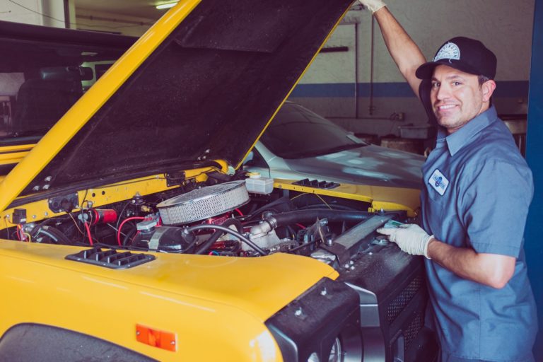 a man in a cap and gloves working on a car engine