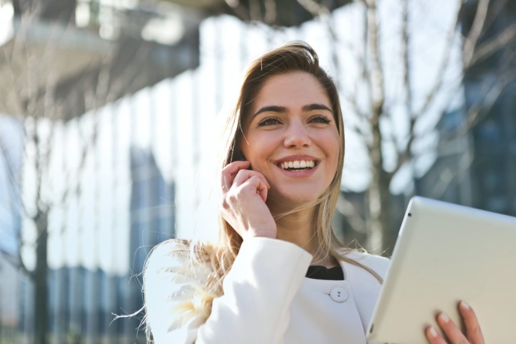 a woman smiling and holding a laptop