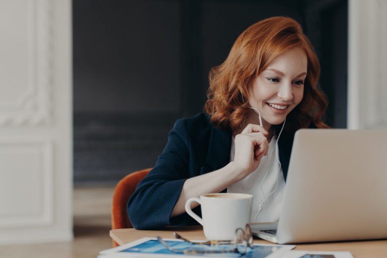 a woman sitting at a table with a laptop and a cup