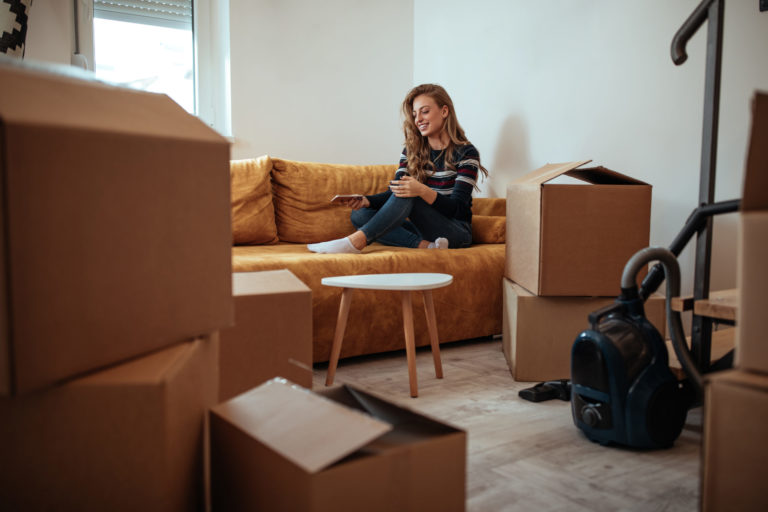 Female sitting on the sofa with the cardboard boxes around her