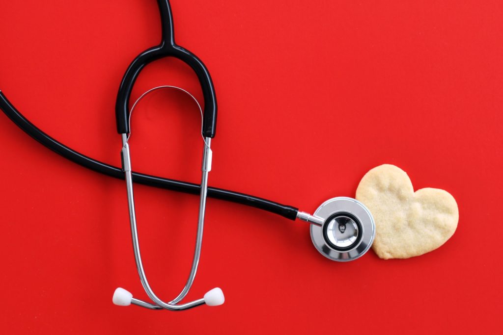Heart health concept - stethoscope heart-shaped cookie on red suffer cardiac arrest or heart attack