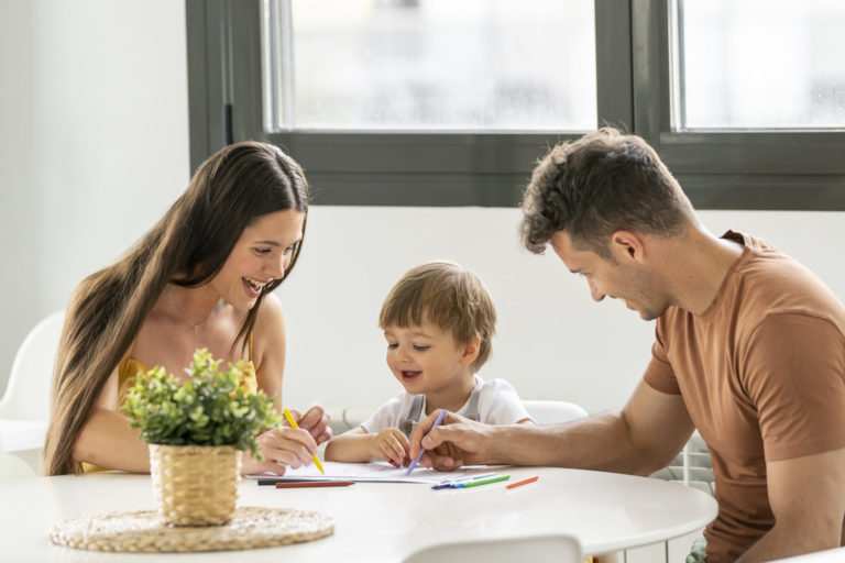 Little boy drawing on the table with his parents
