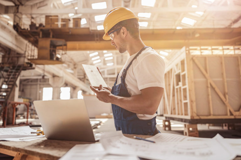 Male worker checking wooden plank at construction site